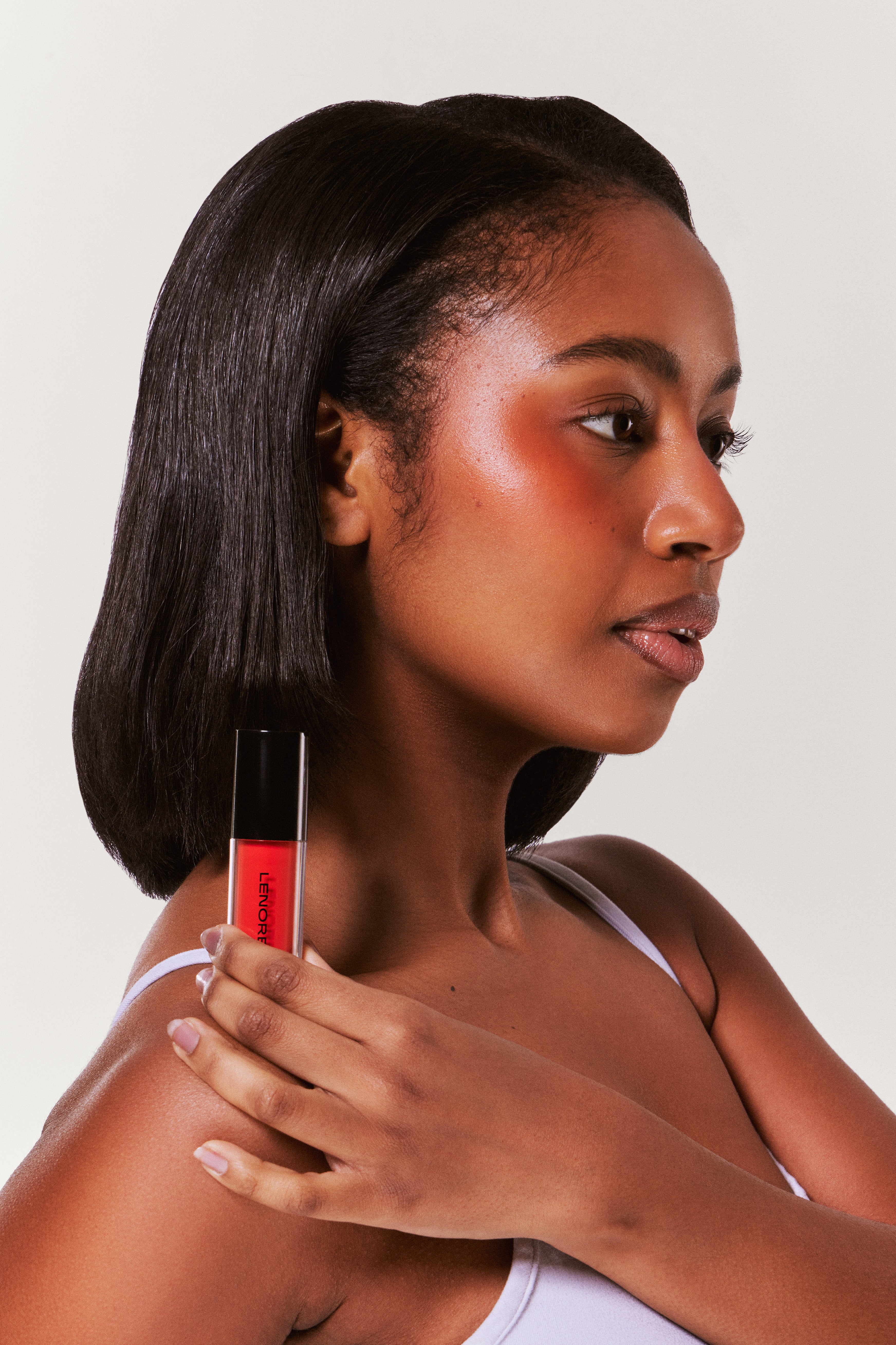 Woman holding a red tube against a neutral background
